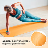 Frau macht Seitstütz auf orangefarbener #DoYourFitness Fitnessmatte – robust, rutschfest, 183x61x1,5 cm, für Yoga und Gymnastik.