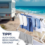 Der EASYmaxx Teleskop-Wäscheständer 800 (auszieh- und klappbar, 8m Trockenlänge) steht platzsparend mit Kleidung und Handtüchern am Sandstrand beim Camper. Im Hintergrund Meer und Himmel. Aufschrift: TIPP! Auch ideal beim Camping.