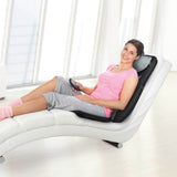 Frau nutzt VITALmaxx Shiatsu-Massagesitz 3D - schwarz zur Rückenmassage mit Komfort und verstellbarem Timer auf weißem Sessel.