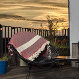 LUMALAND Baumwolldecke / Tagesdecke aus 100 % Baumwolle - ca. 200 x 240 cm - Rubin Rot auf Stuhl bei Sonnenuntergang draußen.
