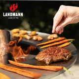 LANDMANN Feuerschalen-Wagen + Plancha-Grill KORREO mit Steak und Gemüse auf der Plancha-Grillplatte bei offenem Feuer.