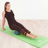 Frau nutzt #DoYourFitness Faszienrolle Ishana Graffiti Braun/Blau zur Massage und Muskelentspannung auf grüner Yogamatte.
