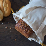 LUMALAND Einkaufsbeutel aus 100% Baumwolle 4er-Set mit Brot und Brötchen auf dunklem Holztisch, nachhaltig und wiederverwendbar.