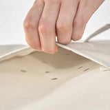 Hand zieht an Belüftungsöffnung der LUMALAND Gartenmöbelabdeckung Grill Abdeckhaube - 183 x 68 x 133 cm - Beige aus wasserdichtem Material.