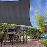 LUMALAND Sonnensegel 100% HDPE mit Stabilisator für UV-Schutz - Rechteck 5 x 6 Meter - Dunkelgrau über Terrasse mit Gartenmöbeln.