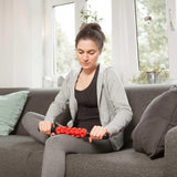 Frau benutzt #DoYourFitness Massageroller Murali 41cm lang Schwarz/Grün zur Selbstmassage auf dem Sofa zur Muskelentspannung.