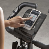 FitEngine Heimtrainer mit Expanderbändern - schwarzes Display mit Handpulssensoren und Smartphone-Halterung beim Training.