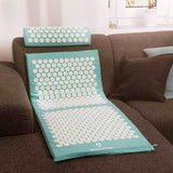 #DoYourFitness Akupressur-Set Bikash mit Massagematte und Entspannungs-Kopfkissen in Blau auf Sofa liegend.
