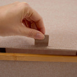 Hand hebt Deckel der LUMALAND Aufbewahrungsbox mit Bambus-Rahmen Rechteckig hoch - 3er-Set - Taupe an, Stofftextur sichtbar.