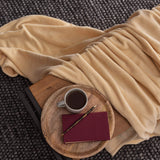 LUMALAND Kuscheldecke 150x200 cm beige auf Sofa mit Holztablett, Tasse Kaffee und Notizbuch, weiches Coral-Fleece für gemütliche Abende.