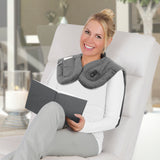 Frau nutzt MAXXMEE Massage-Heizdecke - 3 Massagemodi - grau mit USB-Anschluss beim Lesen auf weißem Sessel.