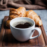 BEEM DIRECT-BREW Filterkaffeemaschine - Glas mit frisch gebrühtem Kaffee und zwei Croissants auf Holztablett.