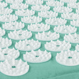 Nahaufnahme von weißen Akupressurspitzen aus Kunststoff auf einer hellgrünen Matte.