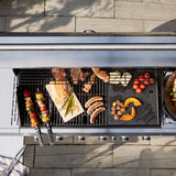 GRILLCHEF Gasgrillküche 6 BR + SB - 121 cm - silber mit emaillierten Gusseisenrosten und Edelstahlbrennern beim Grillen verschiedener Speisen.