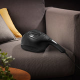 N8WERK Milbensauger Midnight Black Edition auf Sofa, saugt und desinfiziert mit UV-C-Licht und HEPA-Filter ohne Chemie effizient Oberflächen.