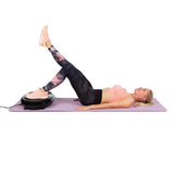 Frau trainiert auf VITALmaxx Vibrationstrainer rund 200W schwarz auf Yogamatte für Ganzkörpertraining zu Hause.