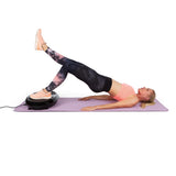 Frau trainiert Ganzkörper mit VITALmaxx Vibrationstrainer rund 200W schwarz auf Yogamatte mit Beinübungen und Expanderbändern.