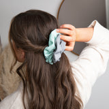 Frau trägt fairtye Scrunchie - grau aus Bio-Baumwolle, elastisch und ohne Metall für starken Halt und vielseitige Frisuren.