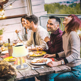 EASYmaxx Solar-Tischleuchte Edelstahl/weiß mit warmweißem LED-Licht auf rustikalem Tisch bei geselligem Abendessen.