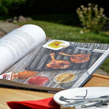 LANDMANN Kugelgrill-Buch zeigt Grilltechniken und Rezepte mit gegrilltem Fleisch und Marinaden auf einer Holzoberfläche.