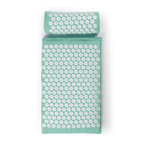 Ein grünes Akupressurmatten- und Kissenset mit weißen runden Druckpunktscheiben, von oben gesehen.