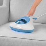 MAXXMEE Milben-Handstaubsauger mit UV-C Licht in weiß/blau beim Absaugen und Sterilisieren eines Sofas.