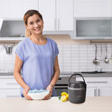 Frau in der Küche mit Eiswürfeln und MAXXMEE Eiswürfelbehälter - 4,5l Füllmenge - schwarz auf der Arbeitsfläche.