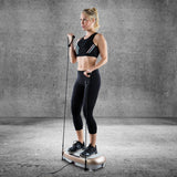 Frau trainiert mit Expanderbändern auf VITALmaxx Vibrationstrainer - Champagner/Grau mit 30 Vibrationsstufen und 3 Trainingszonen.