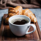 BEEM DIRECT-BREW Filterkaffeemaschine - Thermo zeigt frischen Kaffee in weißer Tasse mit zwei Croissants auf Holztablett.