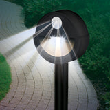 MAXXMEE LED-Sensorlicht mit Bewegungsmelder und Erdspieß, rund, 2er-Set, grau, witterungsbeständig und kabellos im Garten platziert.