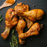 MAXXMEE Heißluft-Fritteuse Digital 4 l in schwarz mit knusprig gegrillten Hähnchenschenkeln auf schwarzem Untergrund.