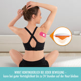 TRIGGin Triggerknopf orange mit pinkem Tape auf der Schulter bei Frau, fördert Durchblutung und löst Muskelverspannungen.